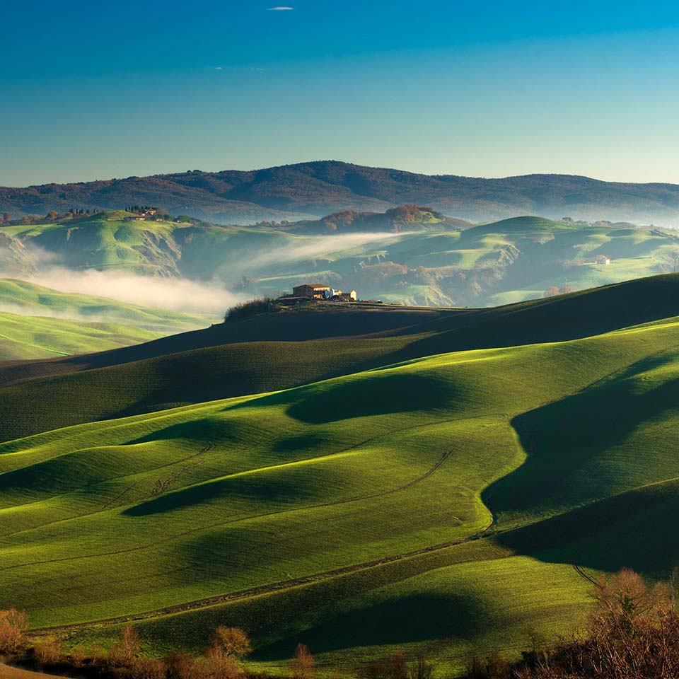 2E8WK7K - green rolling hills in a winter sunny morning in the scenery of crete senesi landscape nearby Asciano, Siena