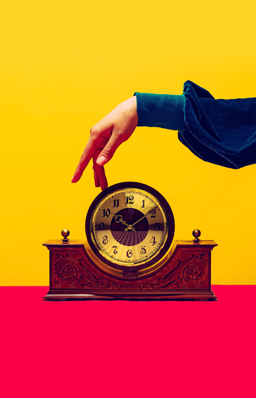 2J2X18G - Retro things, pop art photography. Female hand touching vintage clock isolated on bright yellow background. Vintage, retro fashion style 
