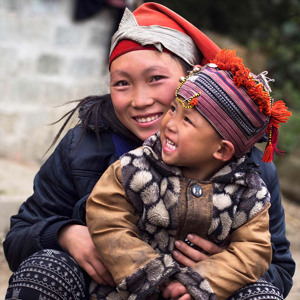 E9R0GC - Happy Hmong woman and child smiling, sitting outside at Giang Ta Chai village near Sapa Town, Lao Cai Province, Vietnam