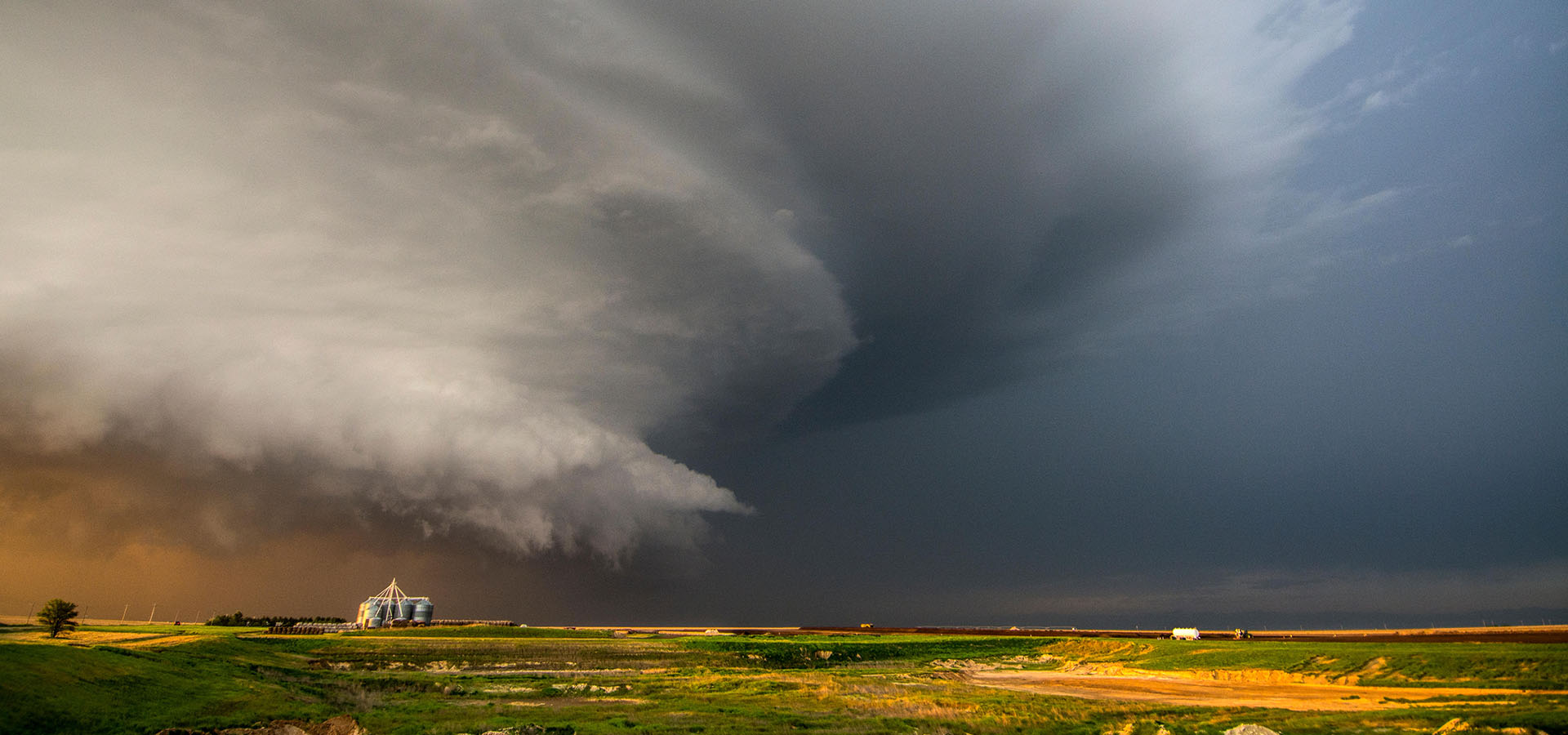 A tornado-producing supercell thunderstorm spinning over ranch land at sunset near Leoti, Kansas
