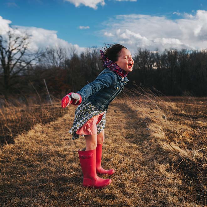 Girl with arms outstretched shouting into the wind 