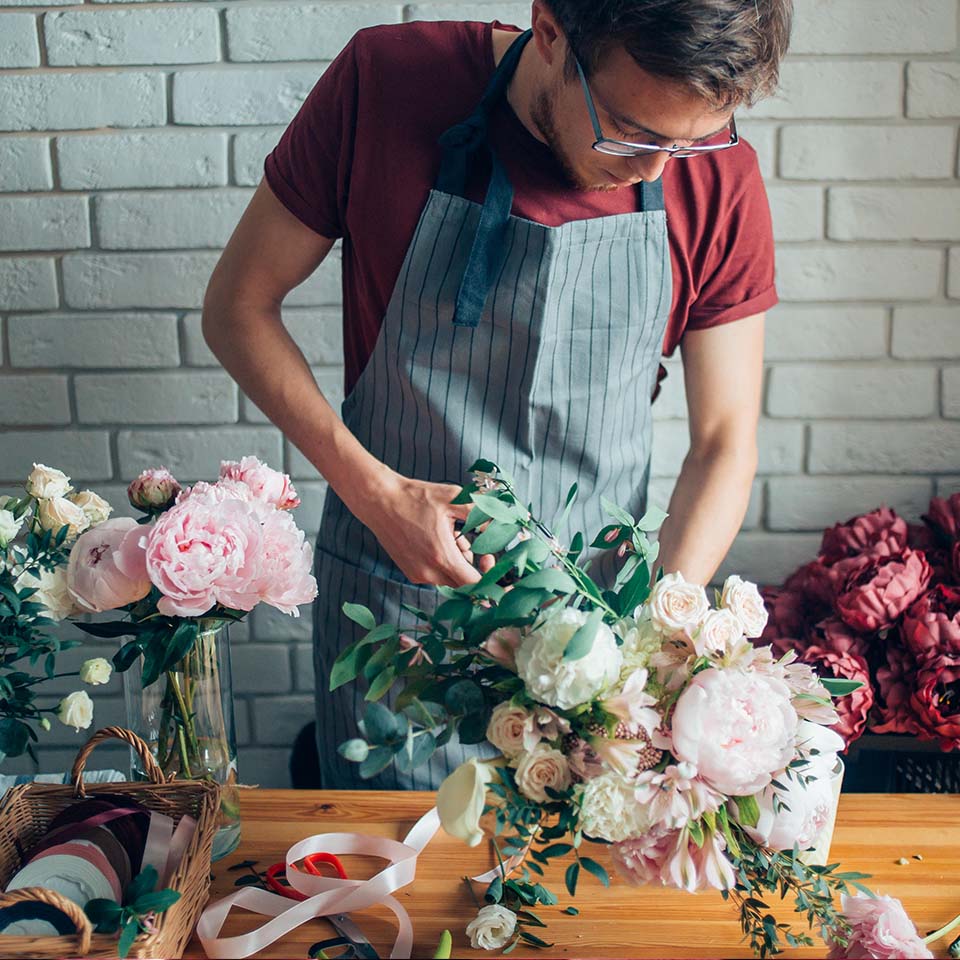 K6CBM8 - Young male florist working at counter in flower shop